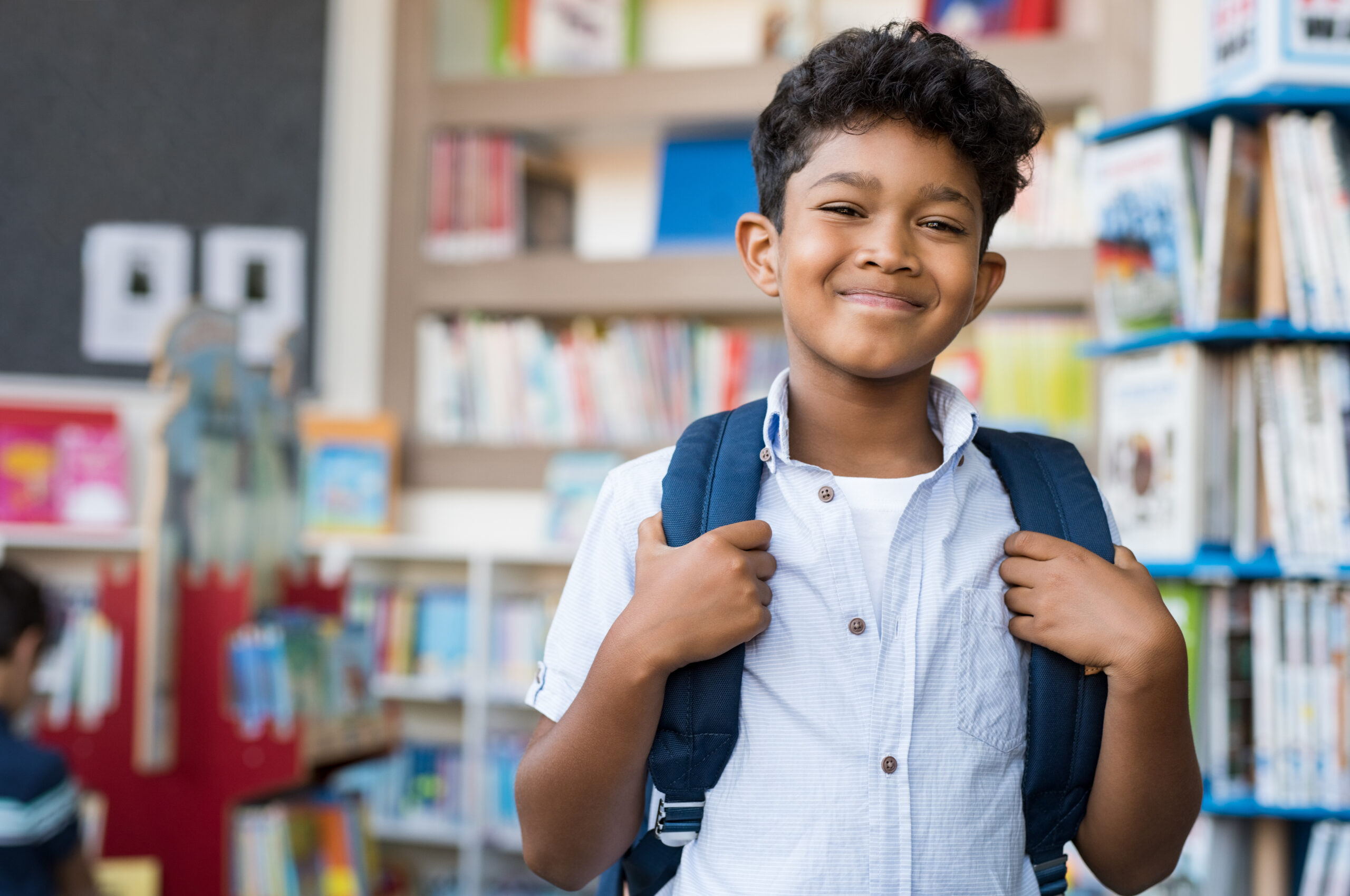 Portrait of young Hispanic boy smiling at school wearing a backpack